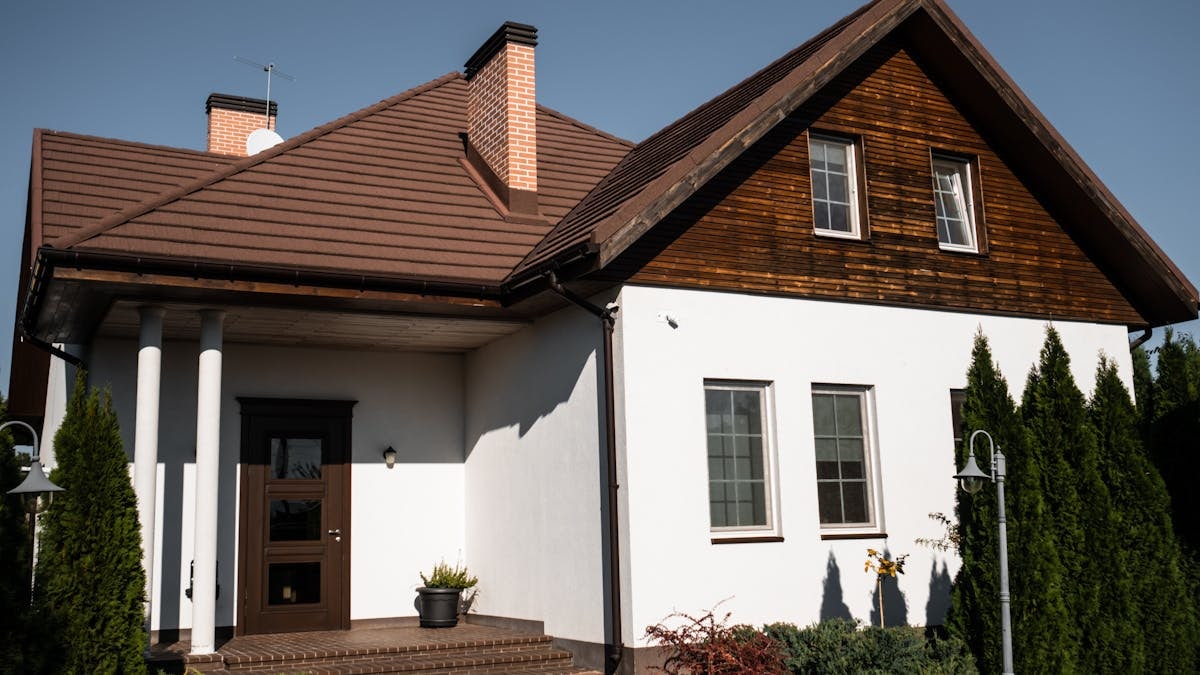 Charming modern bungalow with white facade and brown roof, ideal for architectural themes.